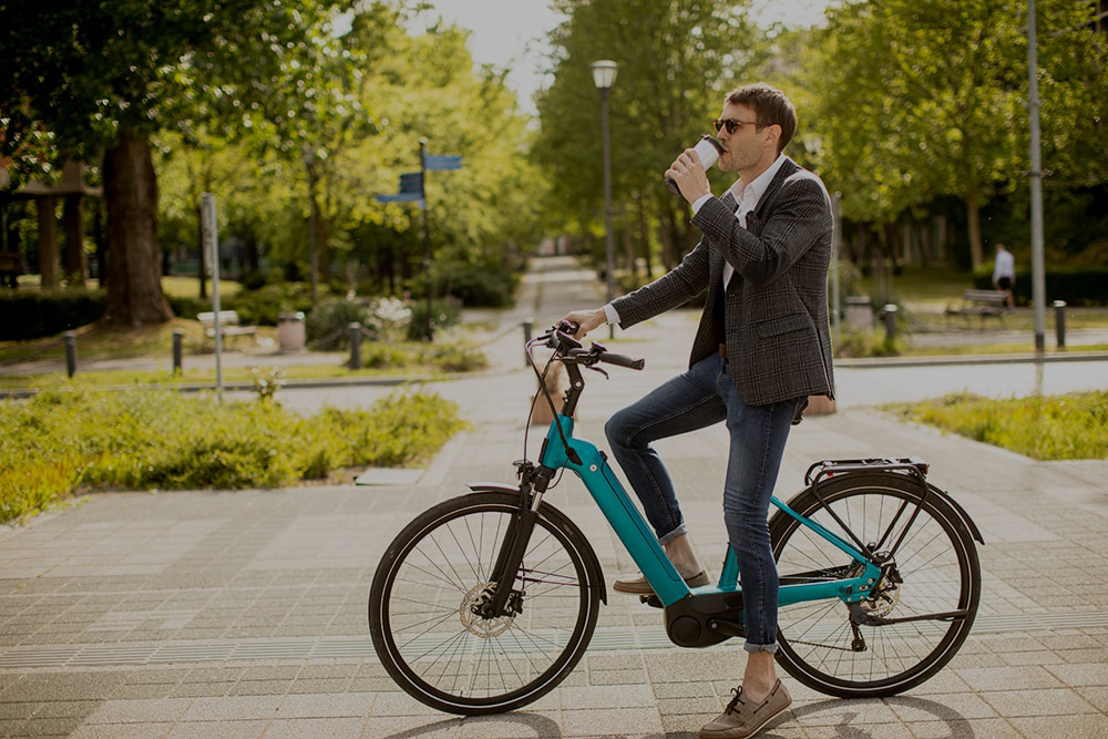 Férfi elektromos biciklizik és kávézik