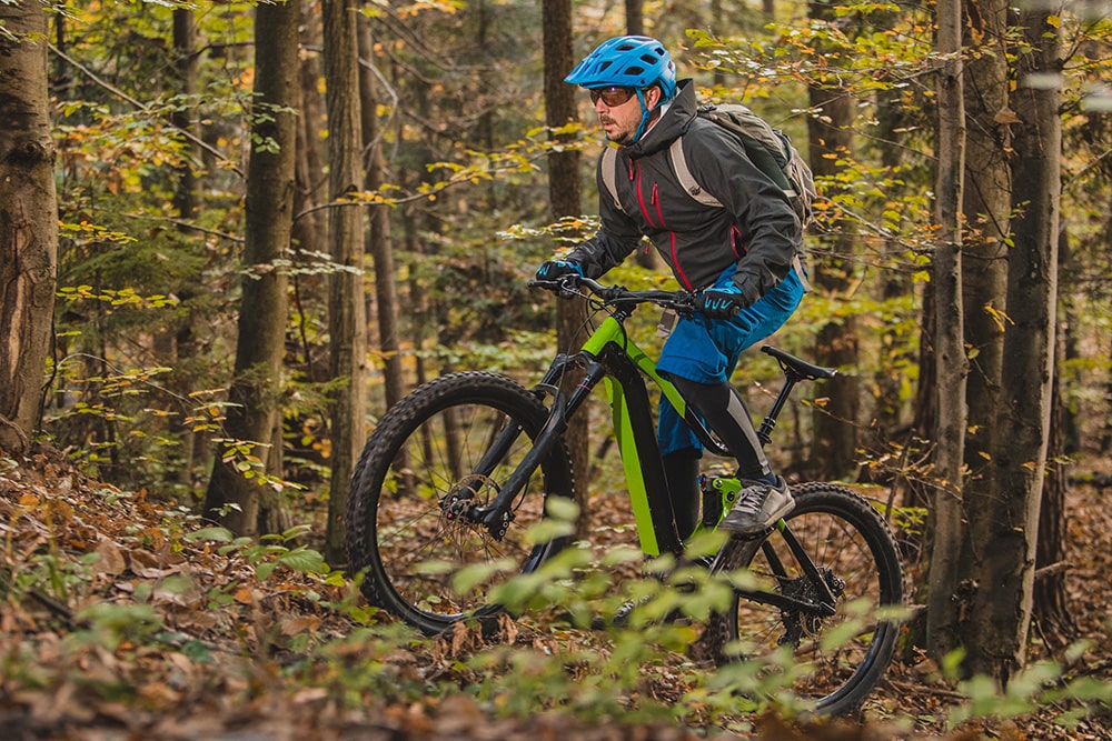 Fiatal férfi erdőben biciklizik elektromos kerékpárral