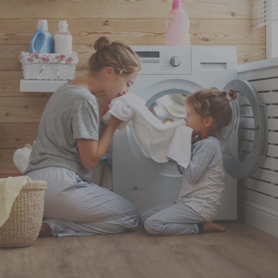 Fiatal édesanya és kislánya a mosógép előtt