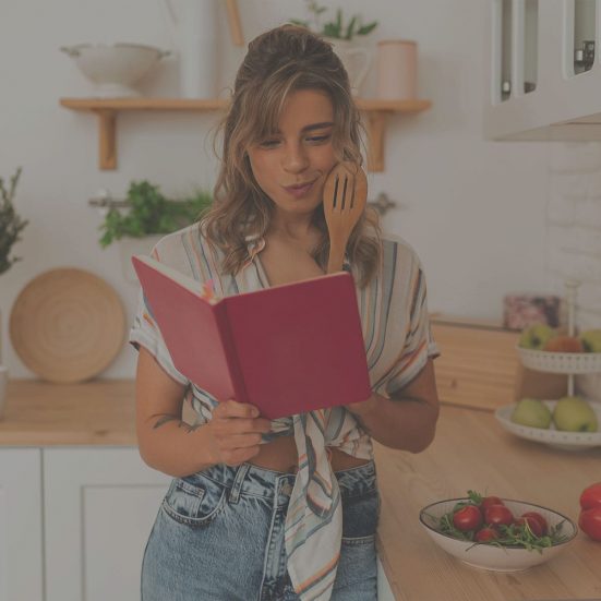 Fiatal nő a konyhában szakácskönyvet olvas